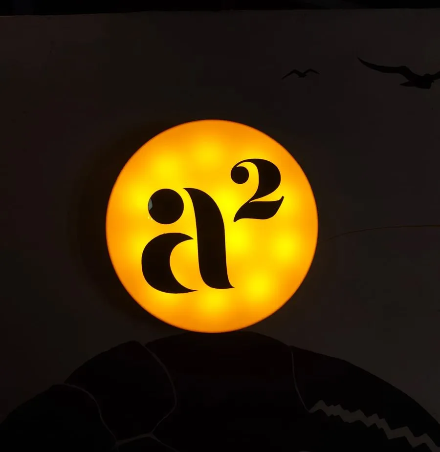 The a² sign lit at night above the gate.